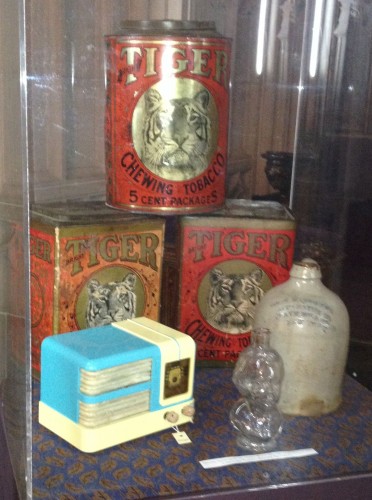 This display case held three Lorillard Tobacco tins, a radio designed by Walter Dorwin Teague (one of the leading designers of the 20th century, a Henry Ward Beecher glass bottle, and a Matthews Soda Fountain stoneware syrup jug.