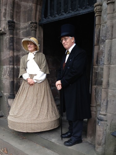 Mrs. and Dr. Mott (Stephanie and Mark Carey) await visitors at the threshold of their mausoleum.