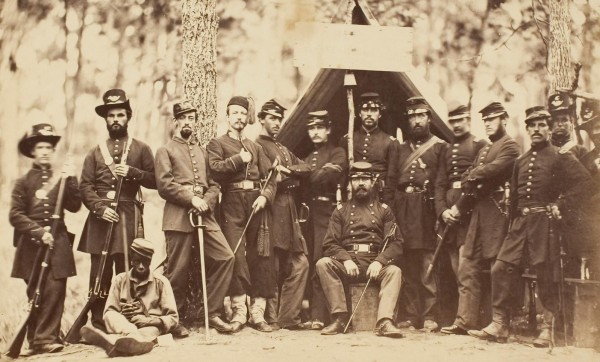 Officers pose with an African-American servant.