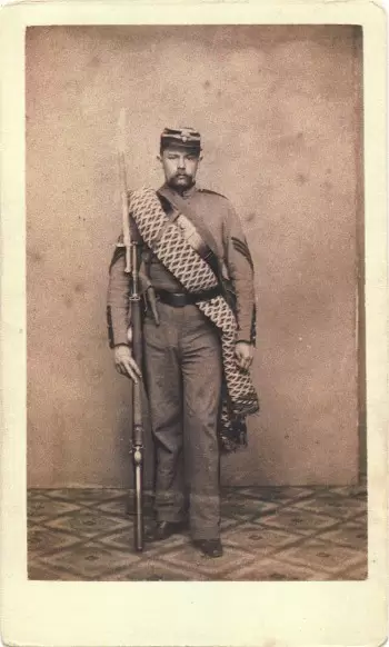 Thomas Lord, Jr., served in the 7th's engineer company; his hat displays the ordnance bomb insignia of that company on its front. He carries his personal blanket. Note that his belt is of dark leather; the other companies in the 7th wore white buff belts.